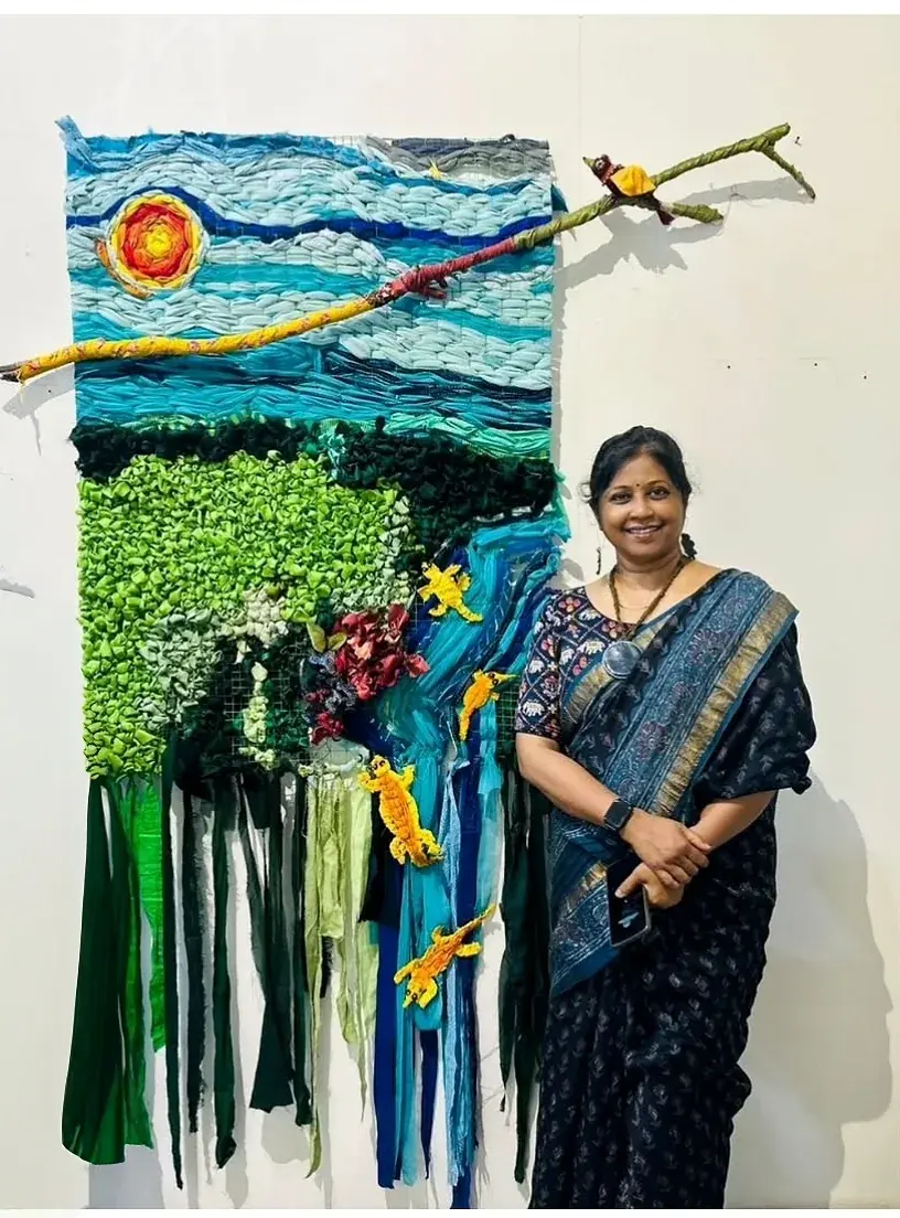 Living Tapestry — a textile wall hanging of blue and green fabric strips forming sky, water and greenery, with yellow appliqué crocodiles
