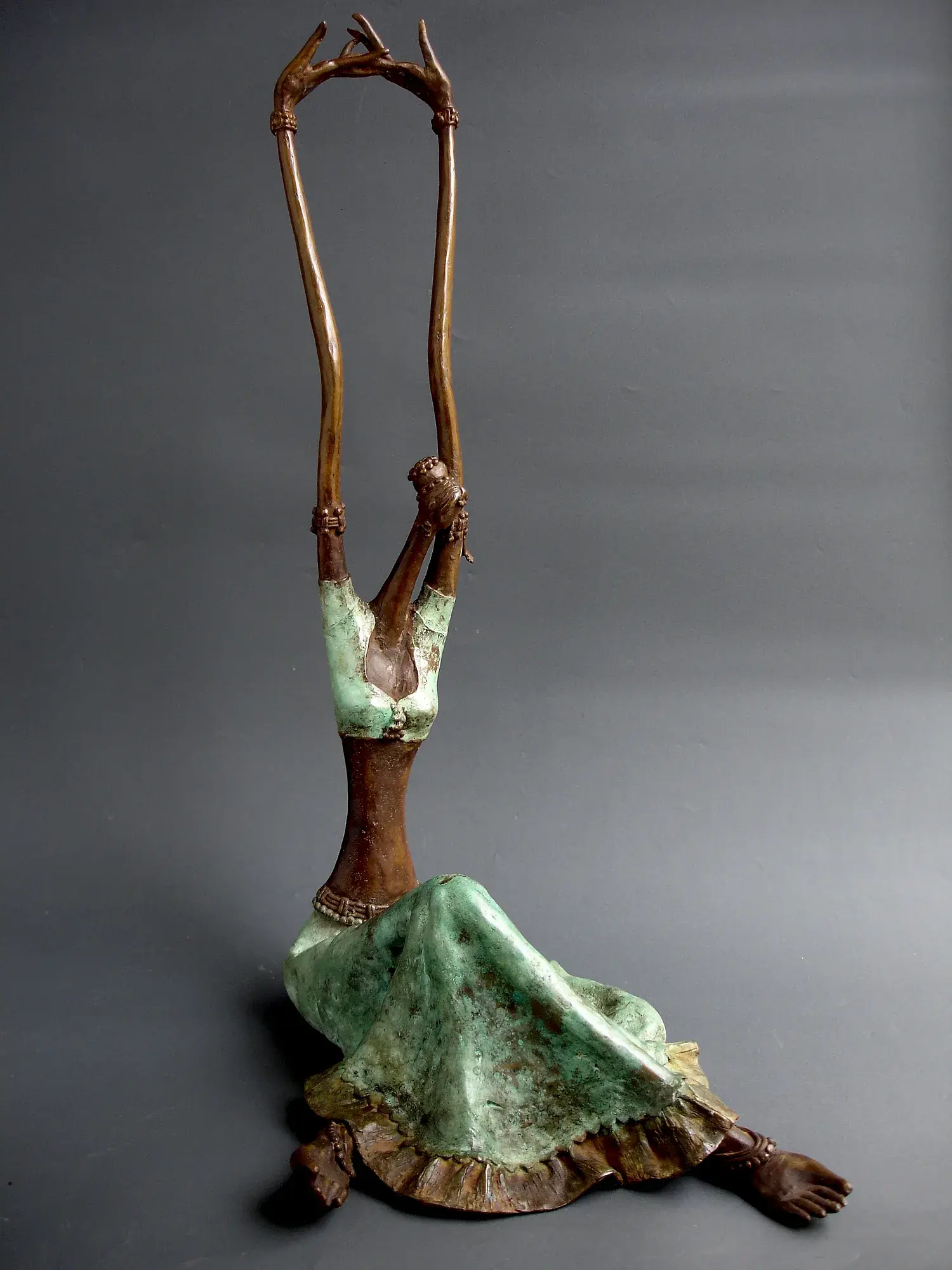 Alasya Kanya I — bronze seated figure with both arms raised straight up, hands nearly touching in a tall triangular silhouette